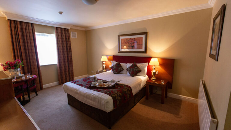 Cosy hotel room with warm lighting, double bed, and a breakfast tray on the bed at Hamlet Court Hotel.