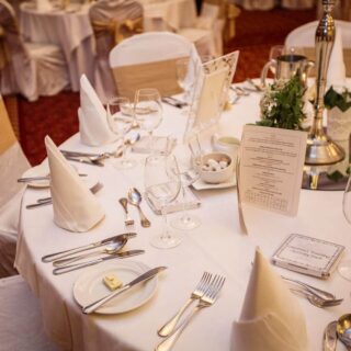 Elegant hotel dining setting with white-linen tables, neatly arranged cutlery, and warm lighting.