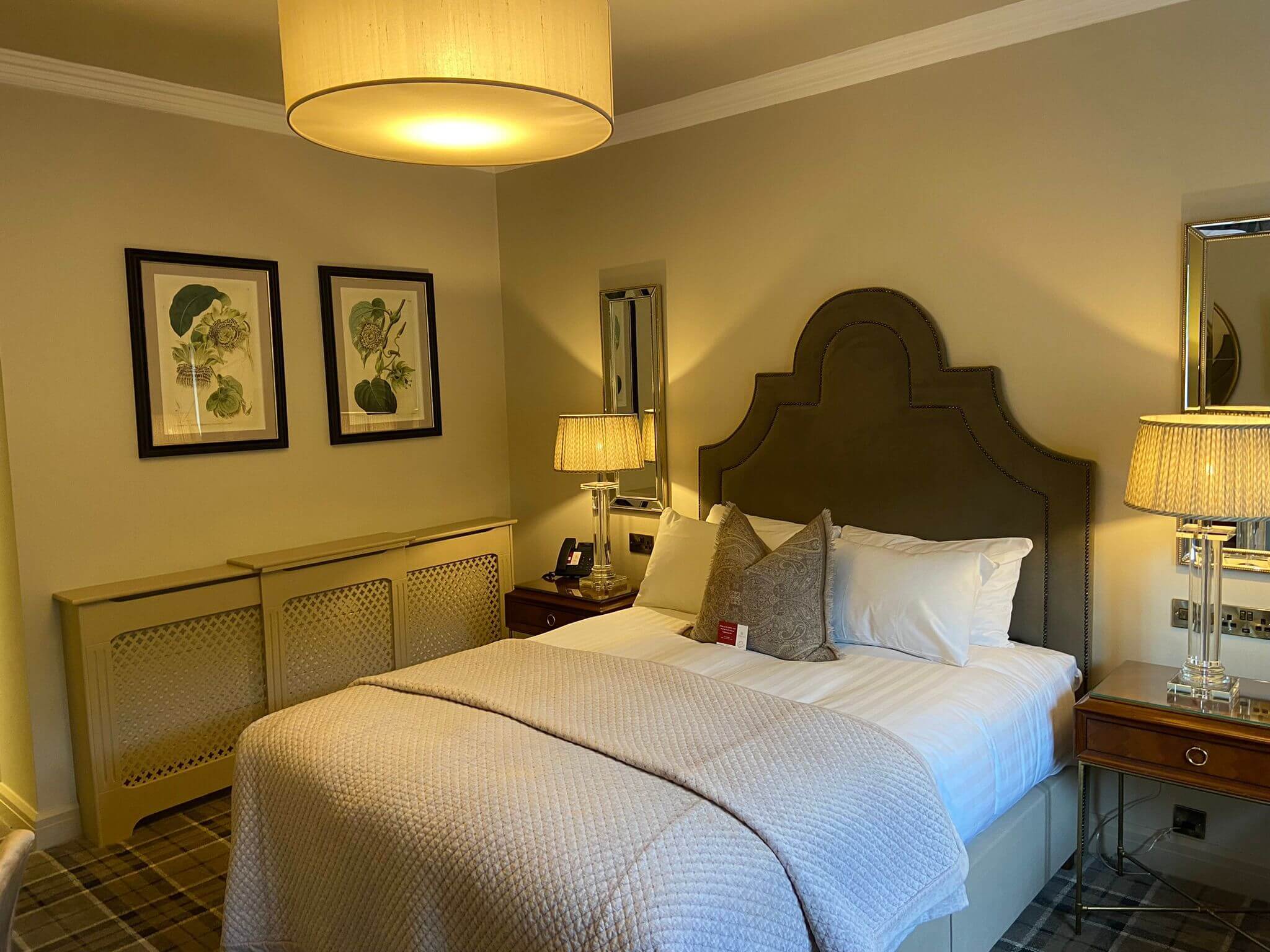 Cosy hotel room with elegant décor and warm lighting, featuring a plush double bed.
