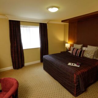 Elegant hotel room with a cosy double bed and warm lighting.