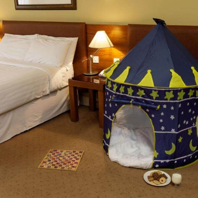 Cosy hotel room with double bed and children's play tent, creating a family-friendly atmosphere.