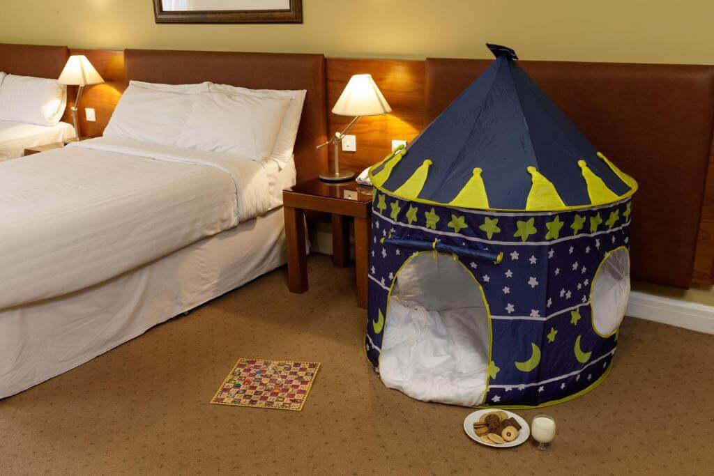 Cosy hotel room with tent, bed, and warm lighting