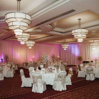 Elegant hotel ballroom set for a warm, inviting dinner with soft lighting and floral centrepieces.