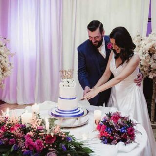 Couple cutting wedding cake at Hamlet Court Hotel, surrounded by flowers and candles.