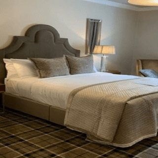 Elegant hotel room with plush bed, soft lighting, and cosy seating area.