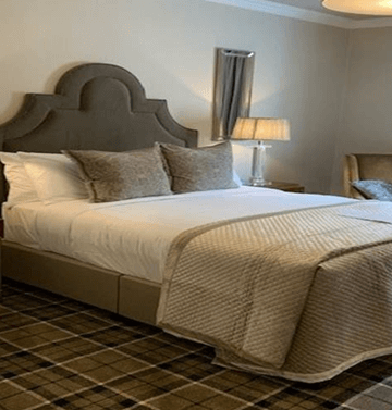 Elegant hotel room with plush bed, soft lighting, and cosy seating area.
