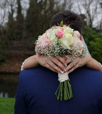 Bridal couple embracing by serene riverside at Hamlet Court Hotel.