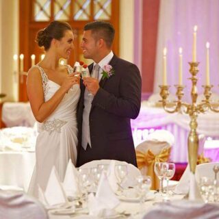 Elegant wedding couple toasting in a warmly lit ballroom at Hamlet Court Hotel.