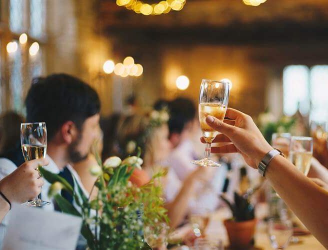 Guests toasting at elegantly decorated dining table in warm, inviting hotel setting.