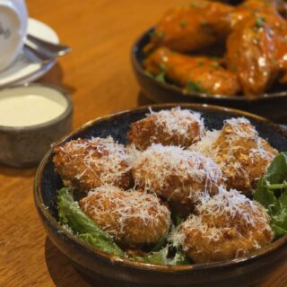 Crispy appetisers with cheese and greens on a wooden table at Hamlet Court Hotel.