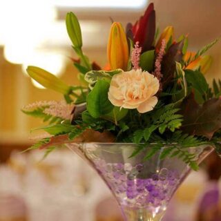 Elegant floral centrepiece in warm, inviting hotel banquet hall.