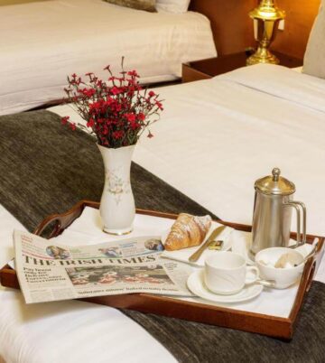Elegant hotel room with cosy bed, breakfast tray, and fresh flowers