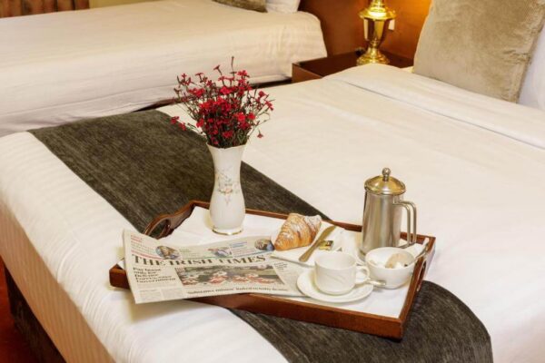 Elegant hotel room with cosy bed, breakfast tray, and fresh flowers