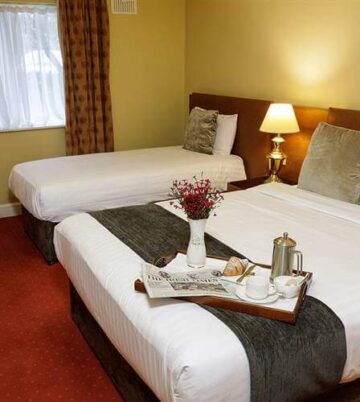 Cosy hotel room with two beds, warm lighting, and a welcoming tea tray.