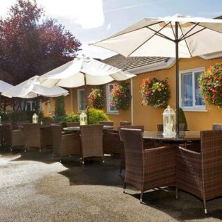 Charming outdoor seating at Hamlet Court Hotel with wicker furniture and floral decor.
