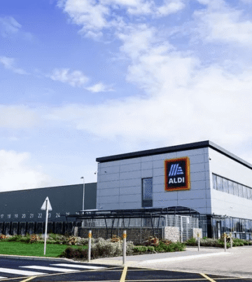 Modern industrial building with Aldi logo under a blue sky.