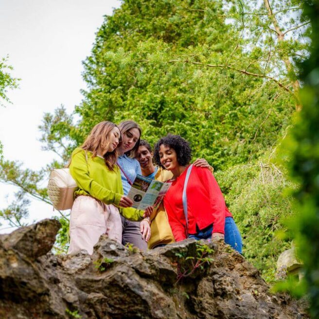 Guests enjoying nature at Hamlet Court Hotel gardens, exploring with a map on a sunny day.