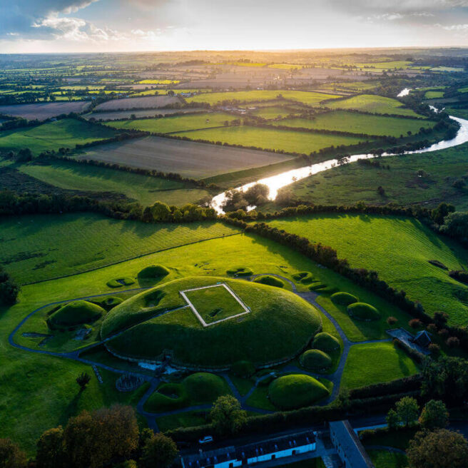 Aerial view of lush green landscapes and river near Hamlet Court Hotel at sunset.