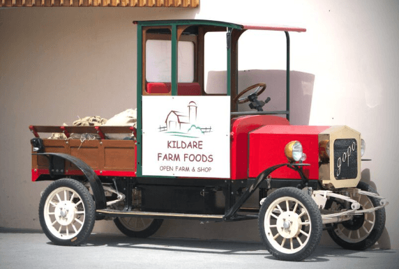 Vintage red truck outside Hamlet Court Hotel with Kildare Farm Foods sign.